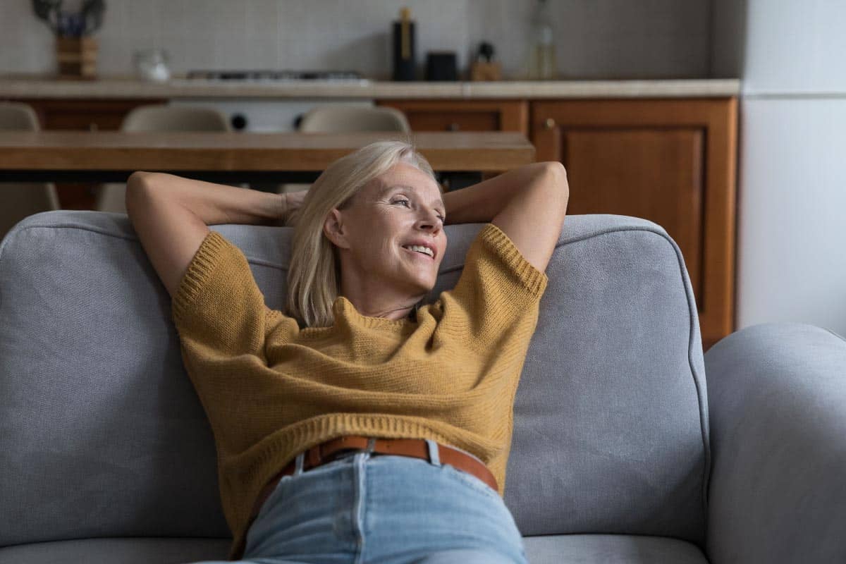 woman in short sleeve sweater on couch. Shutterstock_2174139471.