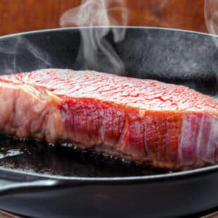 Searing steak in cast iron skillet.