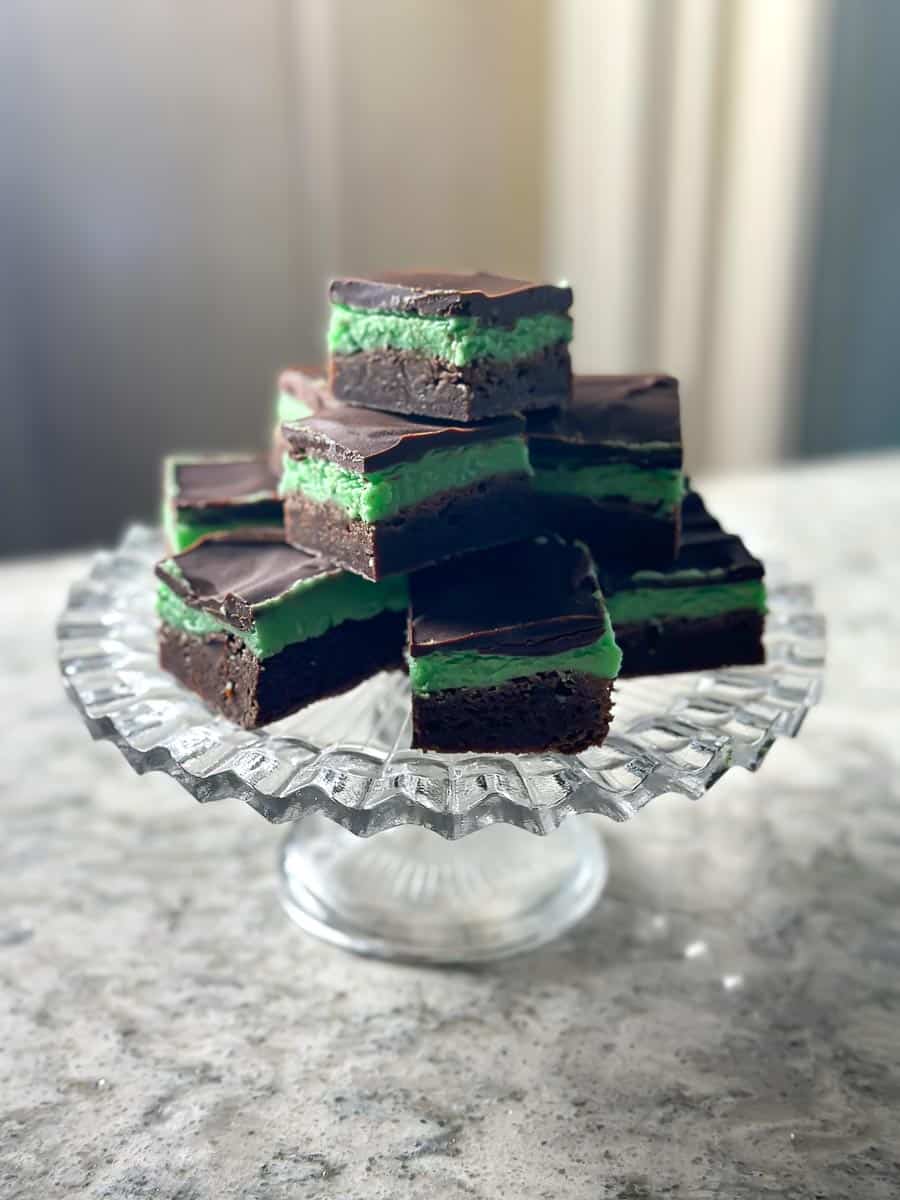 low FODMAP mint brownies cut into squares piled on glass pedestal.