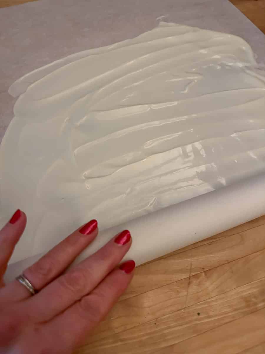 rolling white chocolate up inside parchment.