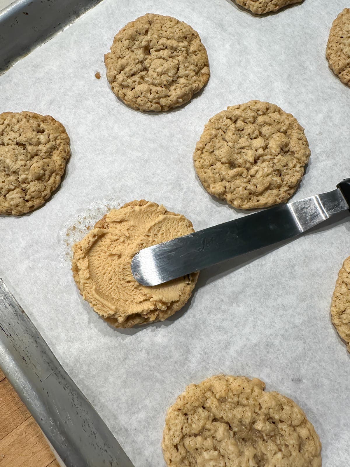spreading peanut butter filling on oatmeal cookie.