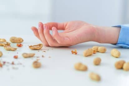 woman allergic to peanuts - hands on floor with peanuts strewn around
