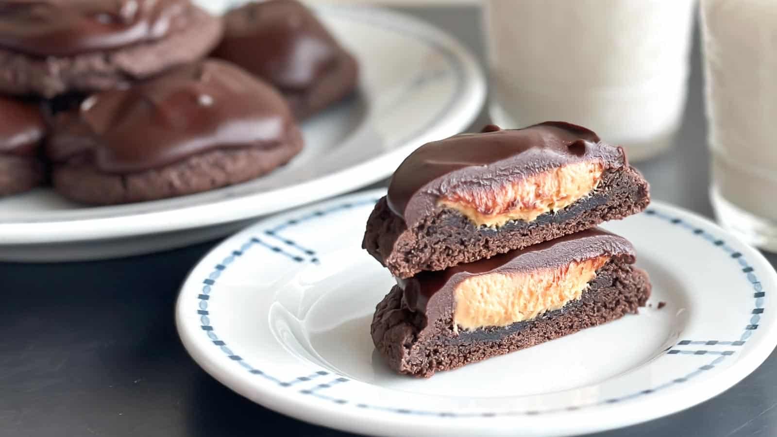 Closeup Low FODMAP peanut Butter Stuffed Chocolate Ganache Cookies, cut in half. With glasses of milk..