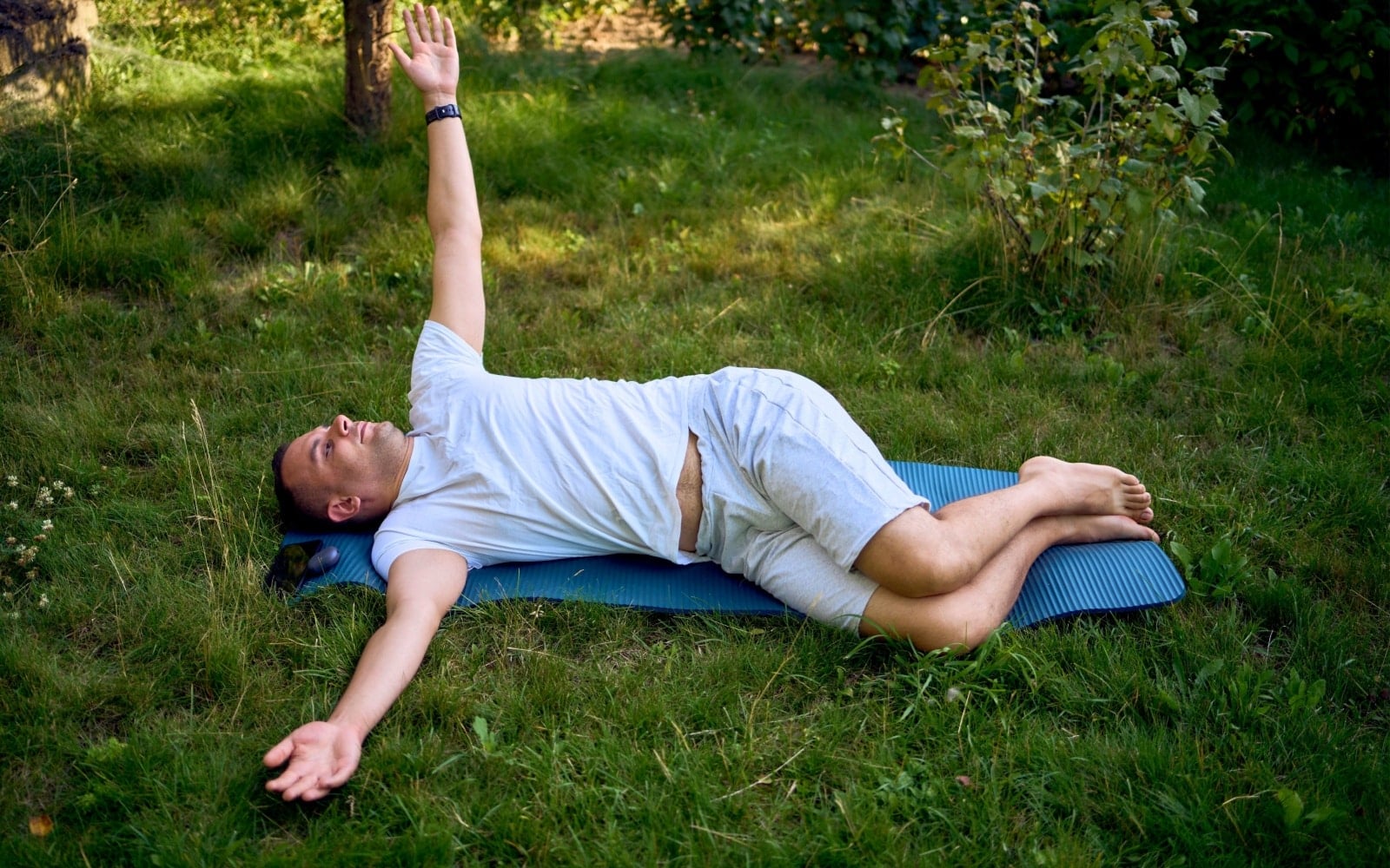 man performs somatic exercises in the garden in the morning