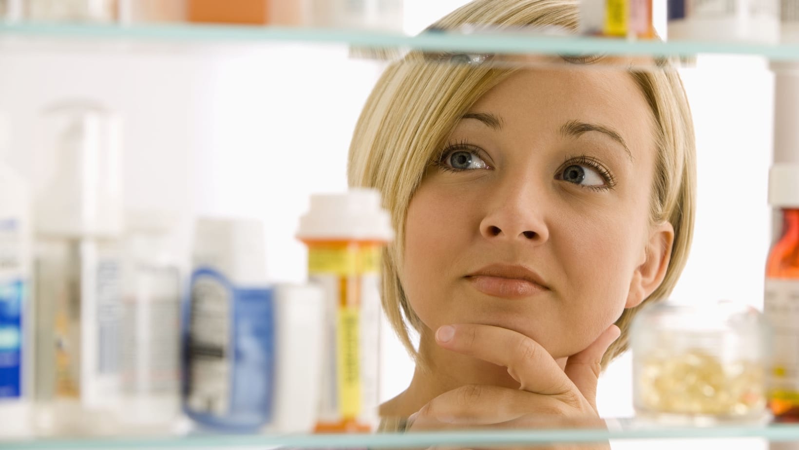 woman looking in medicine cabinet. 