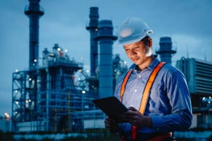 Night shift engineer oil and gas refinery service, male worker hard work in petroleum industry plant dark background.