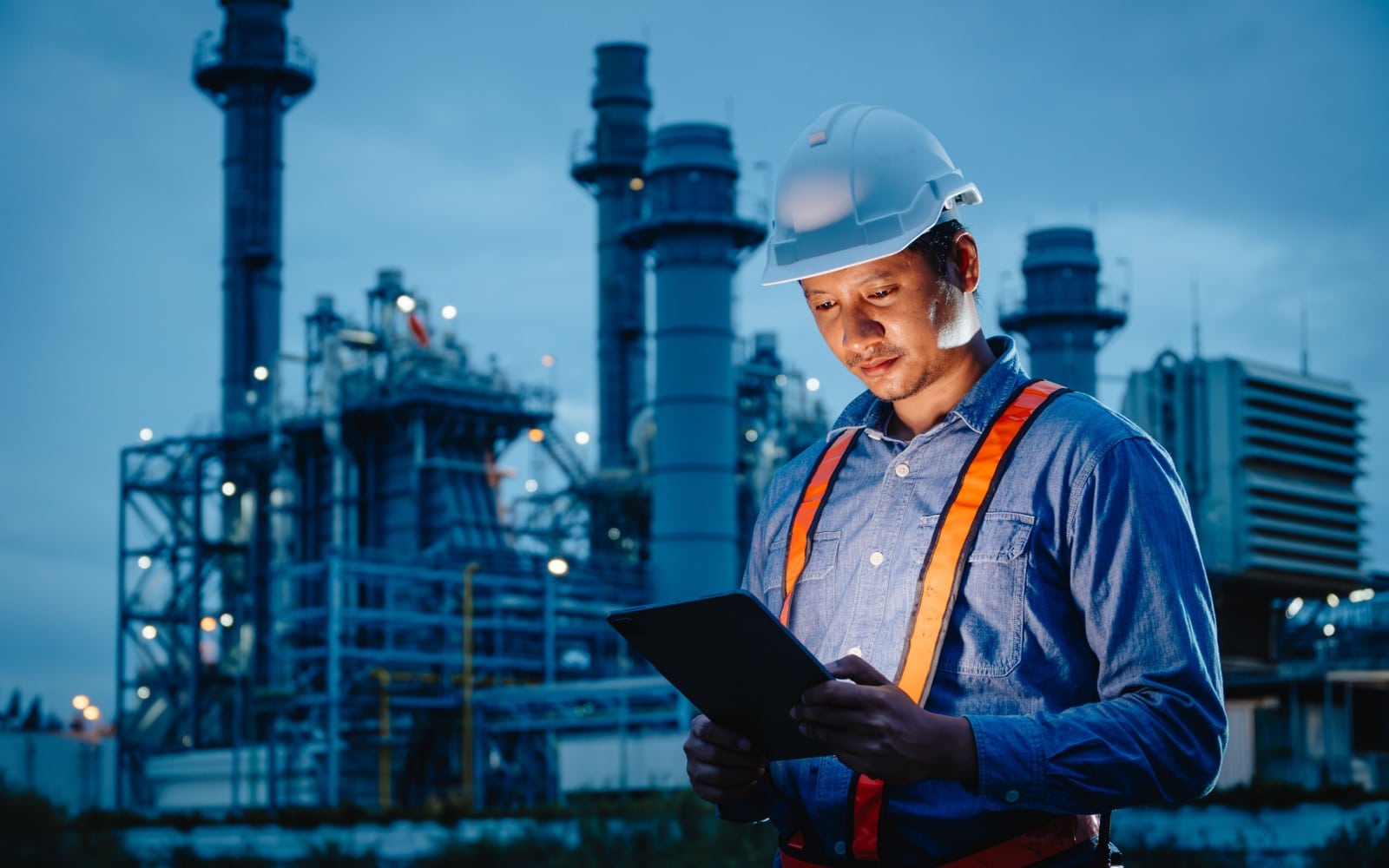 Night shift engineer oil and gas refinery service, male worker hard work in petroleum industry plant dark background.