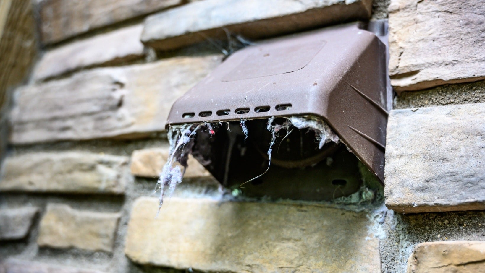 lint hanging from dryer outdoor vent