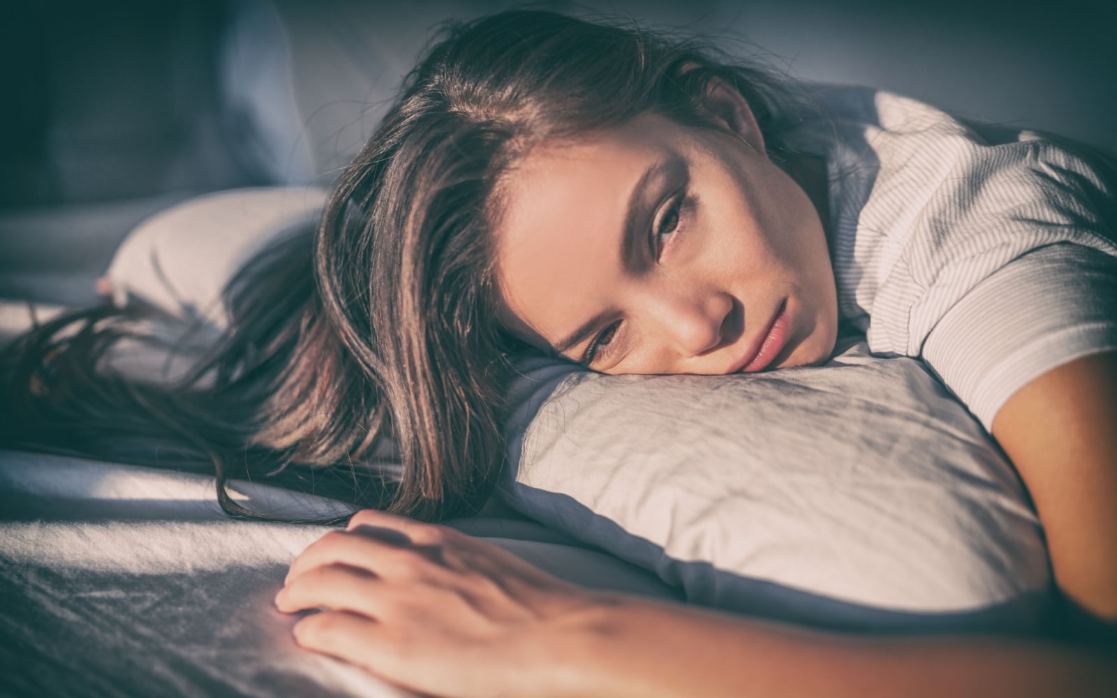 Tired woman lying in bed can't sleep late at night with insomnia. Asian girl with funny face sick or sad depressed sleeping at home.
