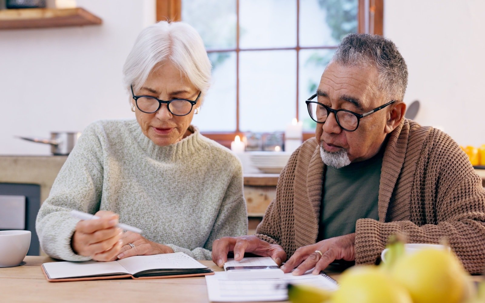 Senior couple, budget and finance notebook with writing and life insurance information for will at table. Discussion, list and paper for process and bills review in print in a retirement home
