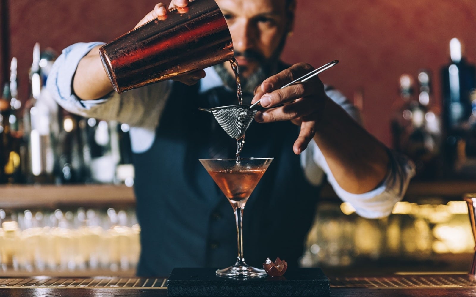 Expert barman is making cocktail at night club.