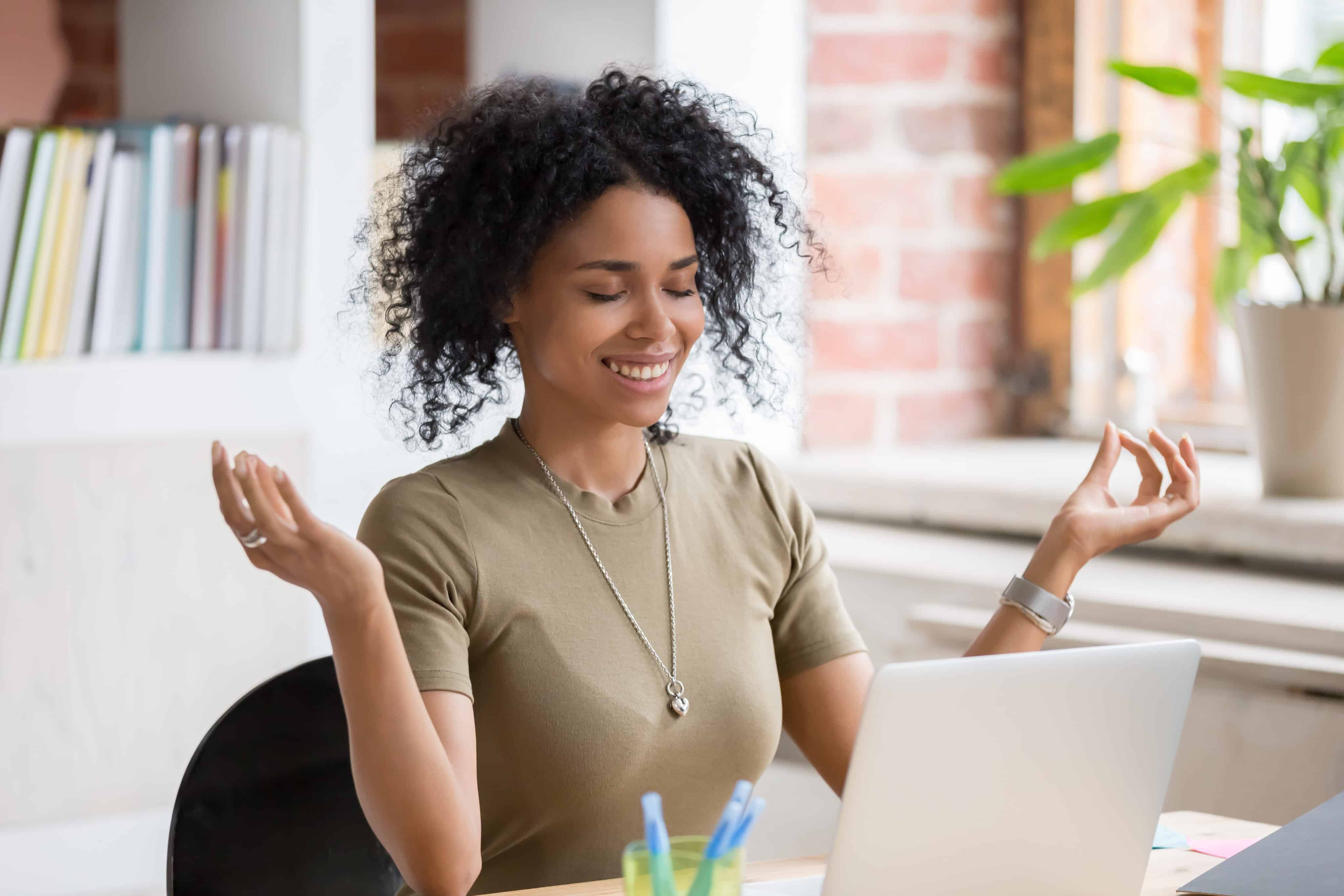 African,Young,Woman,Sitting,At,Table,Opposite,Laptop,In,Workplace.