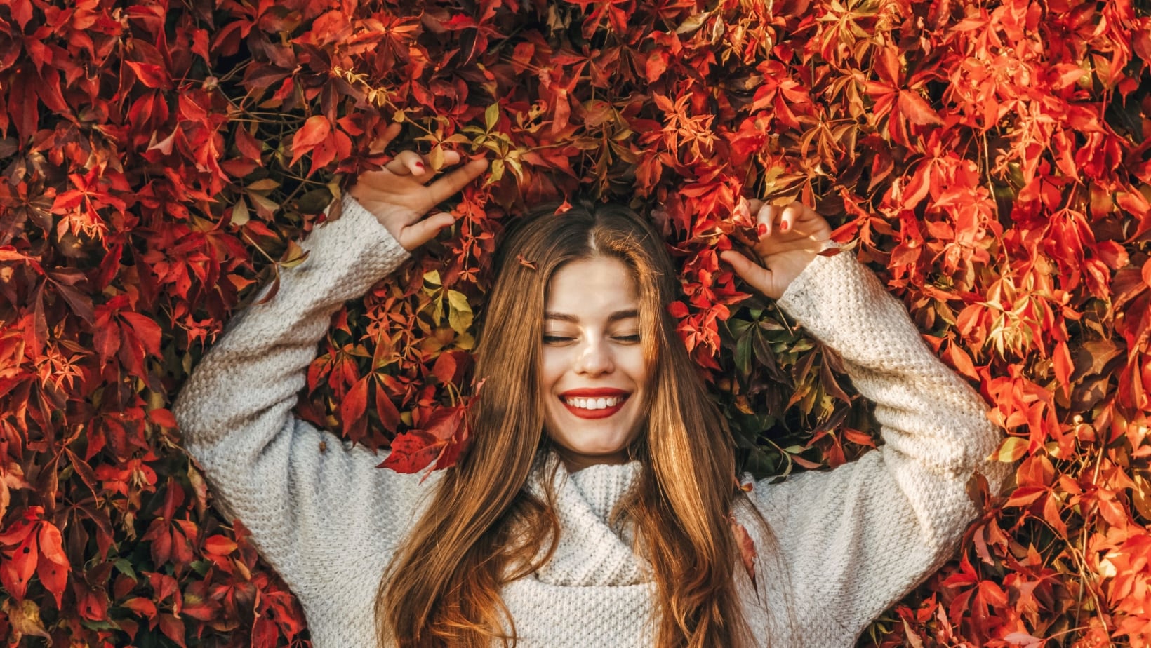 Young woman laying in Fall Leaves. Irene Shy via Shutterstock.