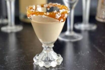 Low FODMAP Salted Caramel Liqueur in glass with caramel and coarse salt.