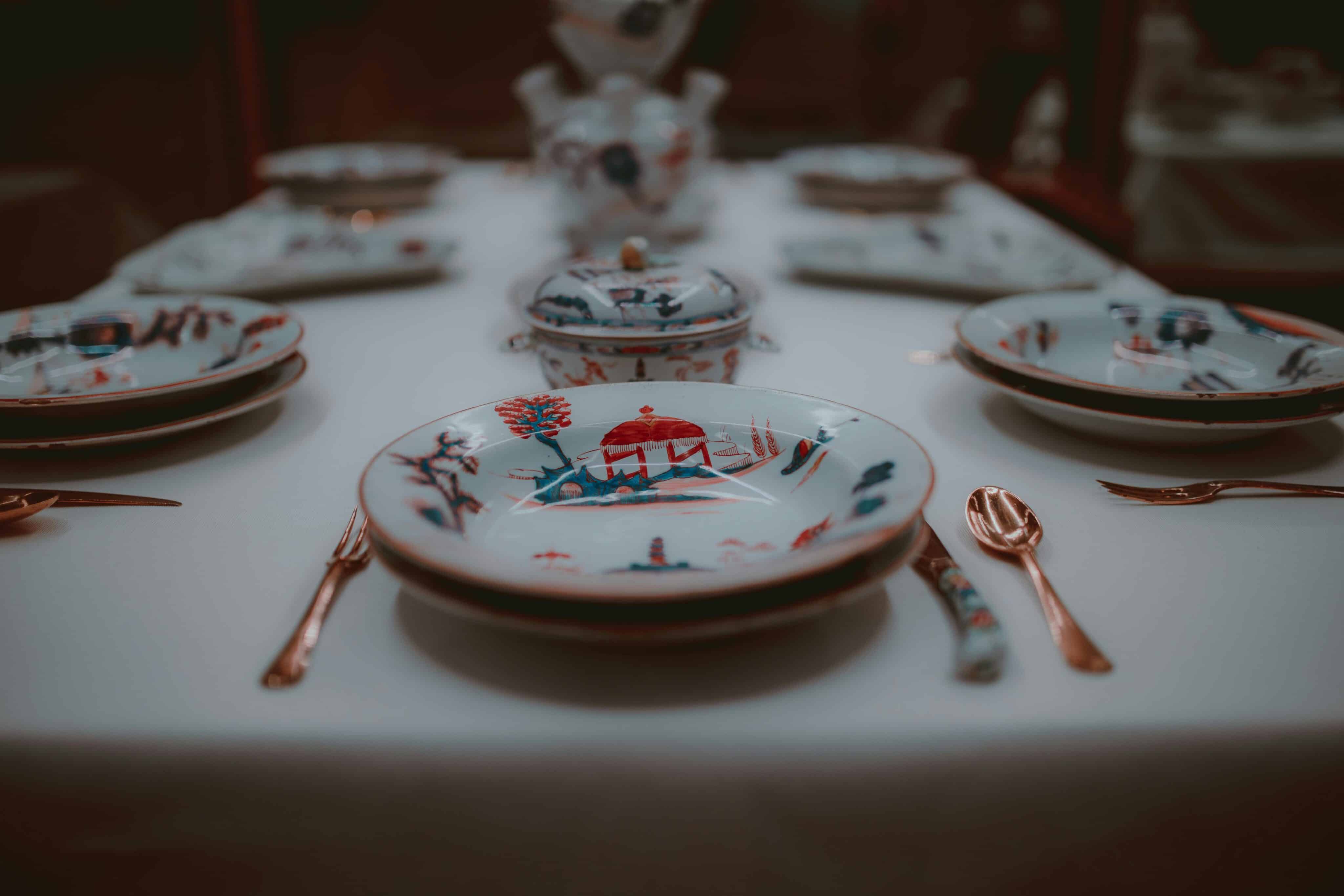 Close-up of a sophisticated porcelain place setting with intricate designs on a dining table.