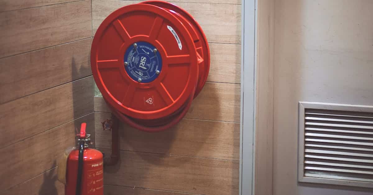 Red fire hose reel and extinguisher inside a building corner.