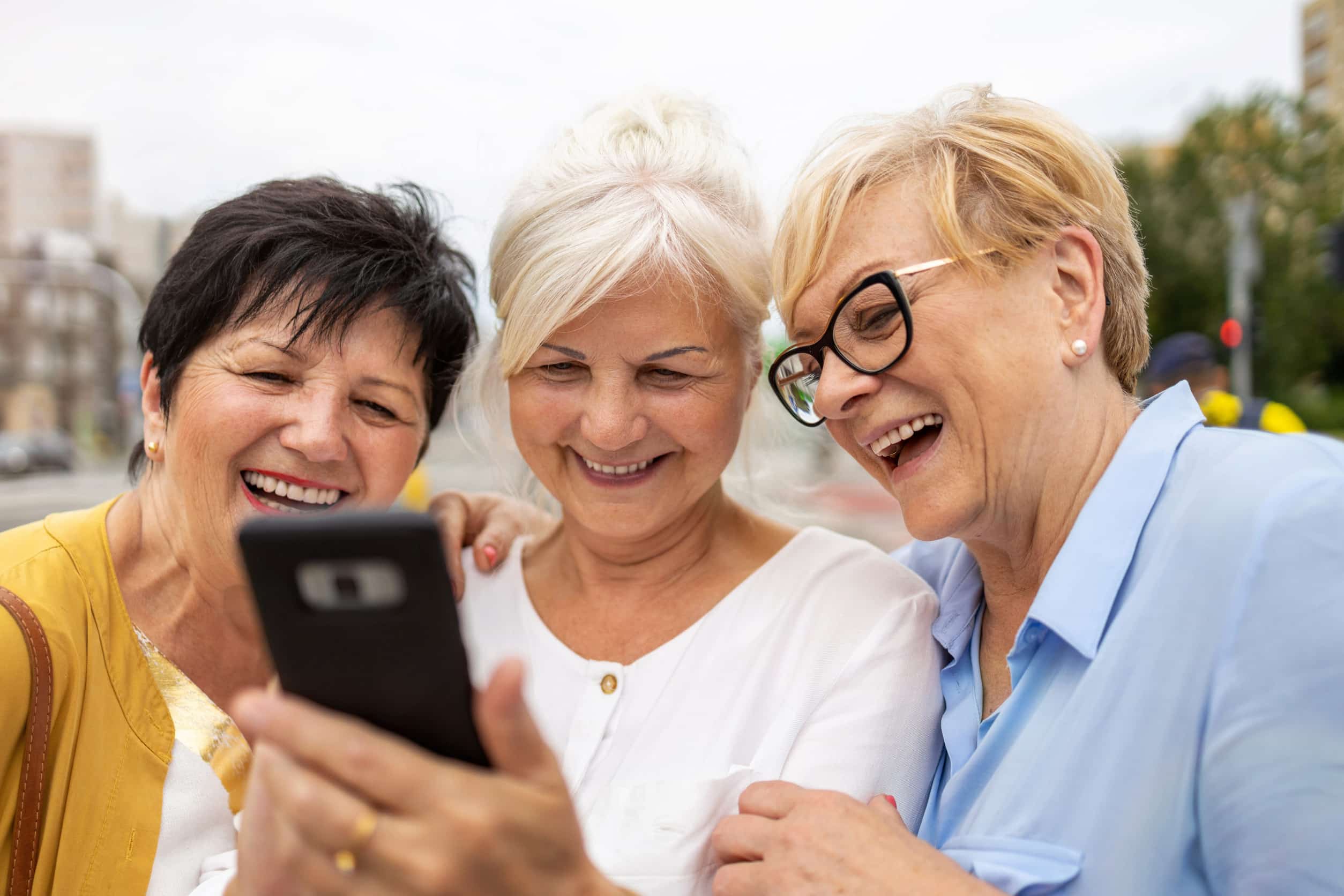 Group of senior women using mobile phone together