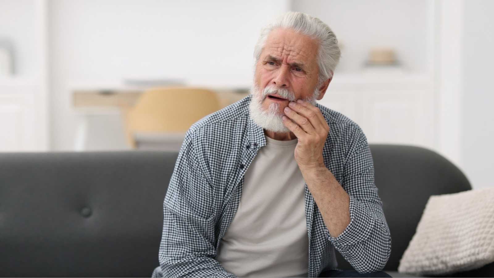Senior man suffering from toothache at home