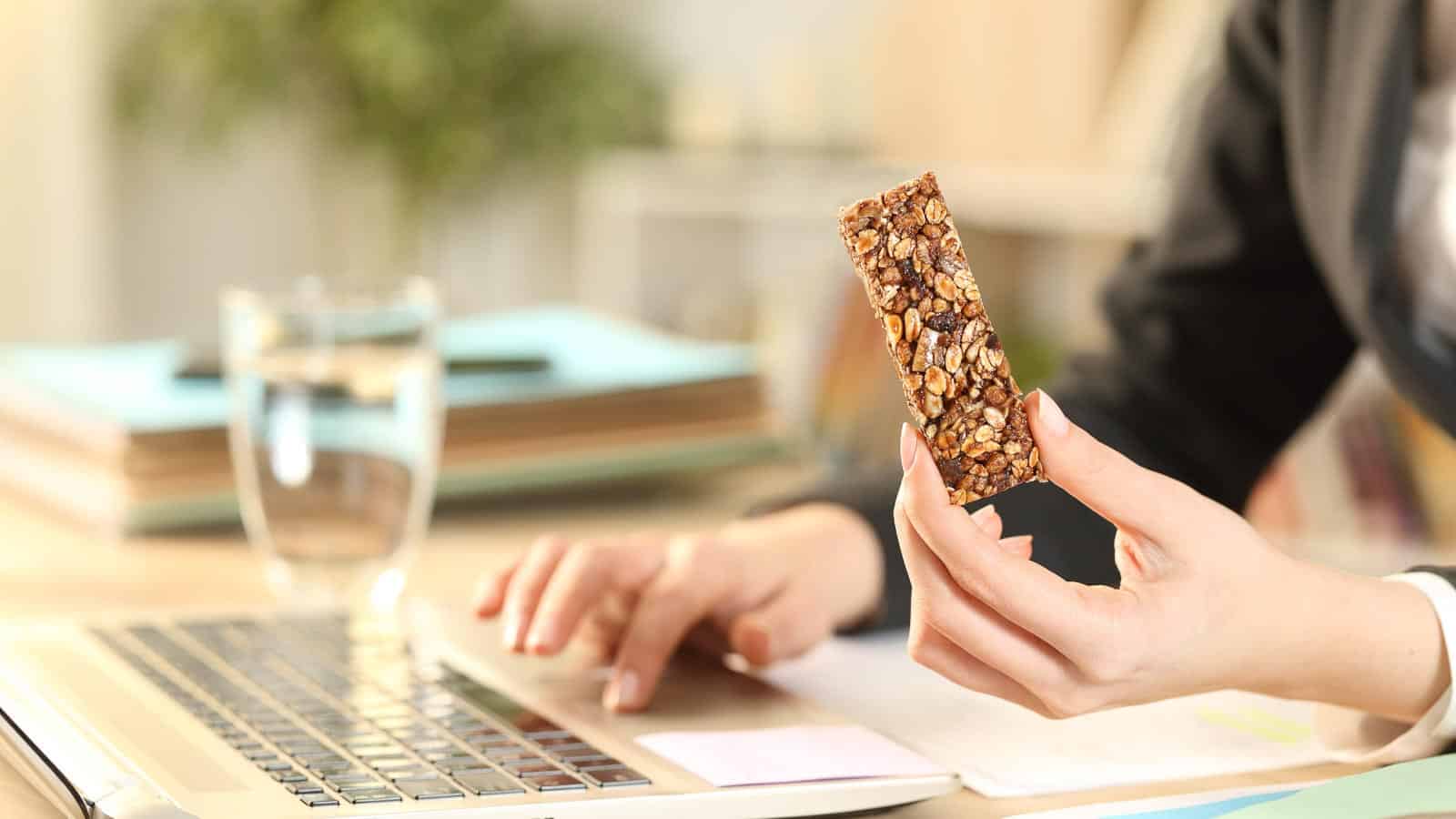 woman working on laptop with granola bar. pheelingsmedia via 123rf