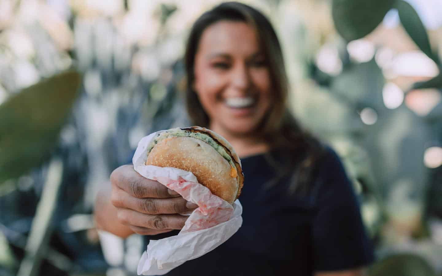 Woman holding burger. RDNE via Pexels