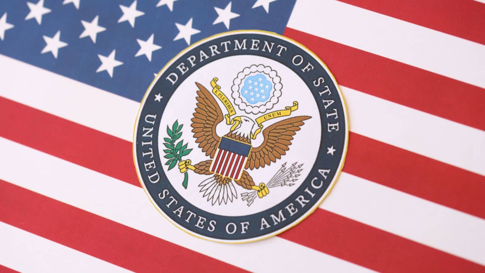 Badge of the Department of State resting on the U.S. Flag