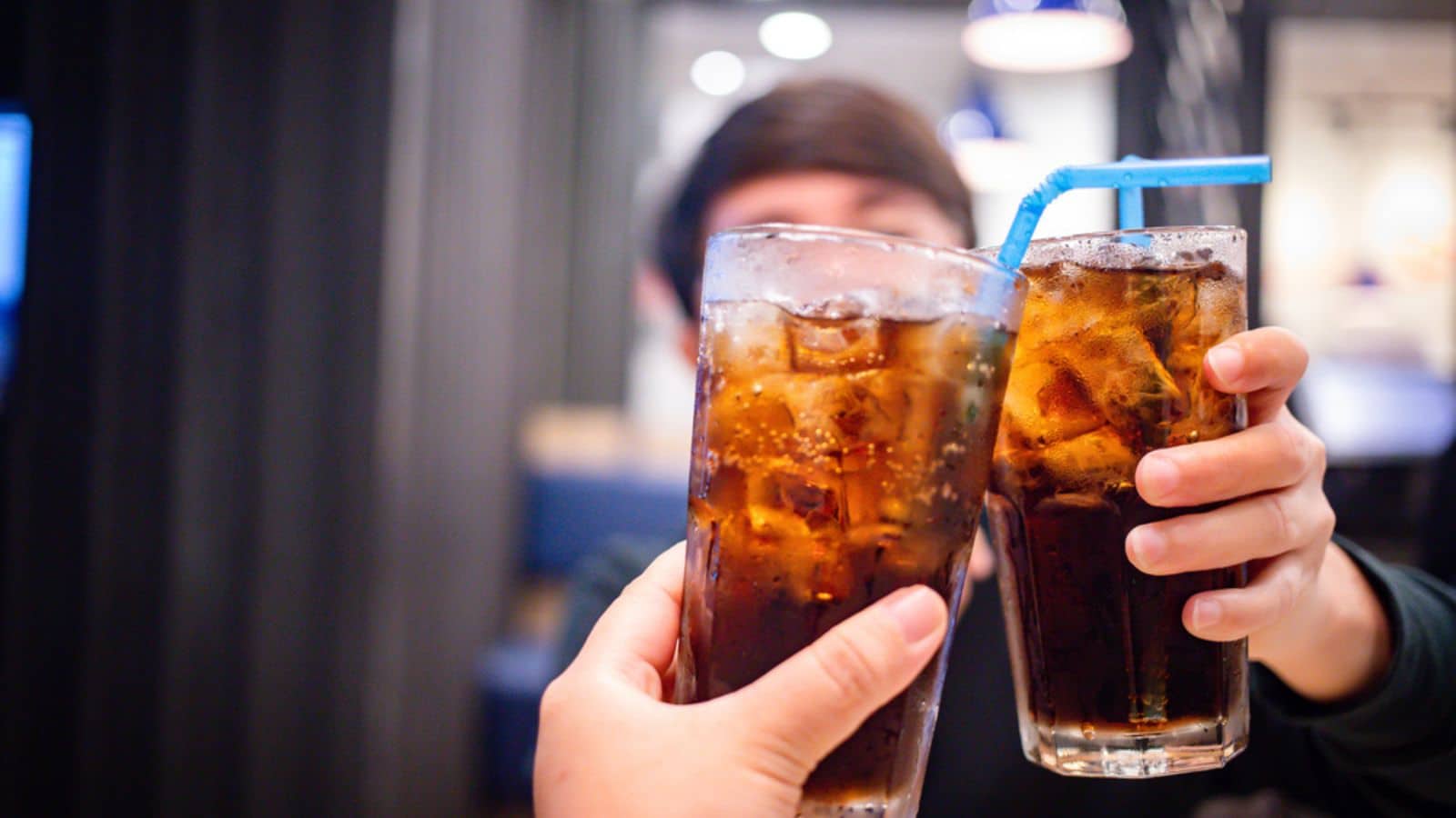 Two people cheering with two glasses of soda