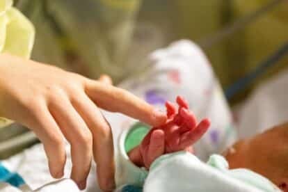 Woman touching baby in hospital