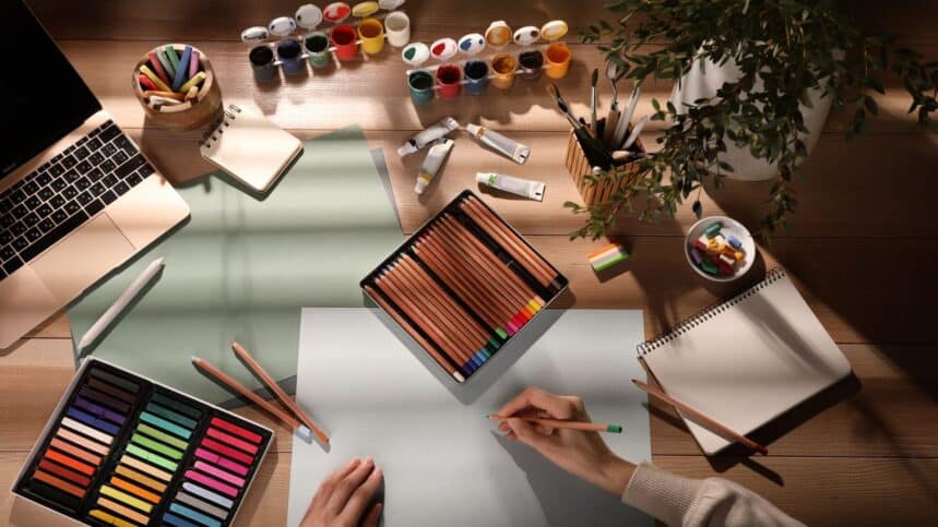 Artist drawing with pastel pencil at table, top view