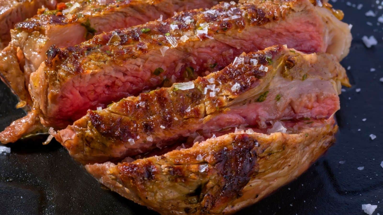 Cut of beef on a black plate with salt