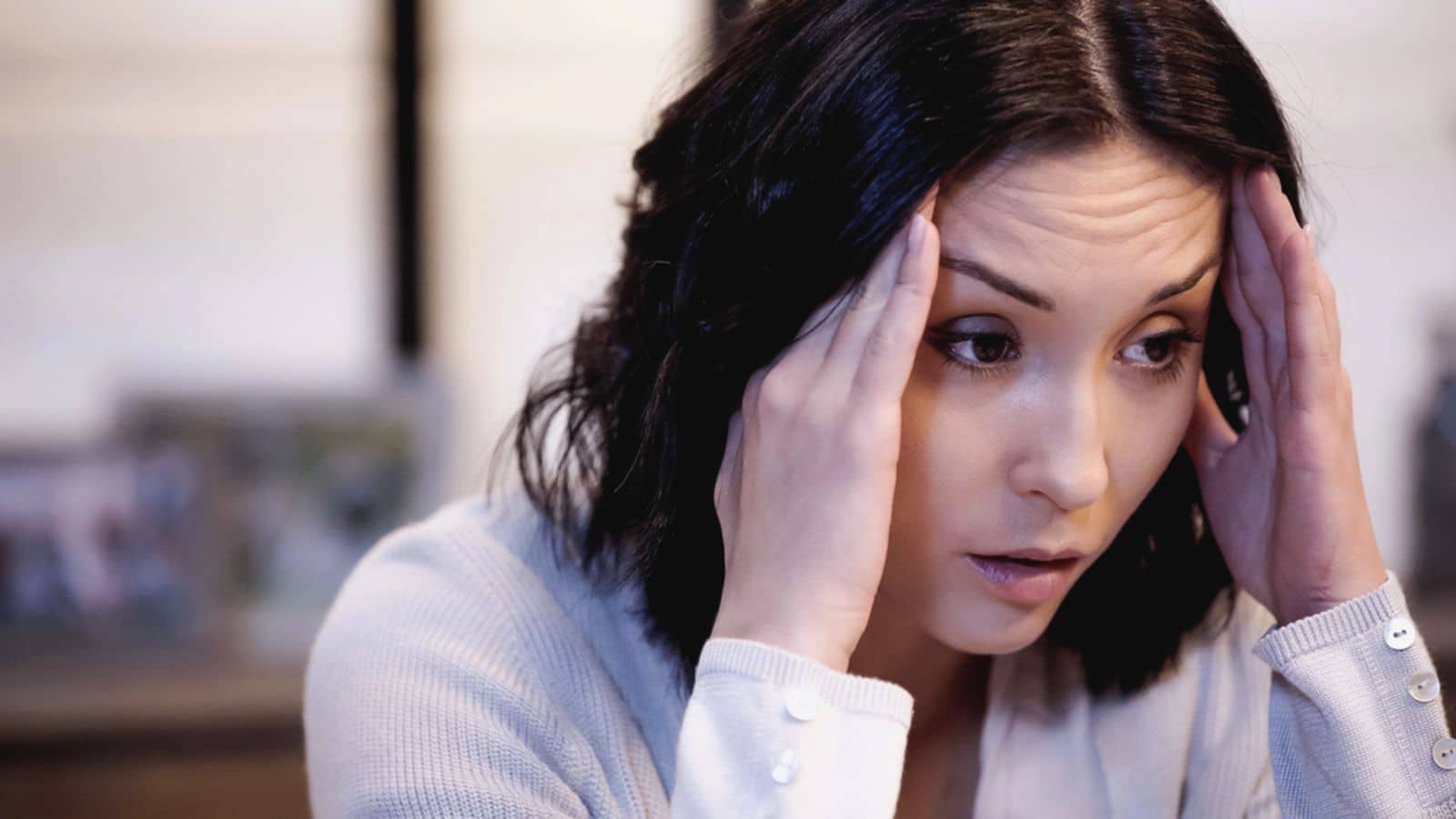 Depressed woman holding her head at home