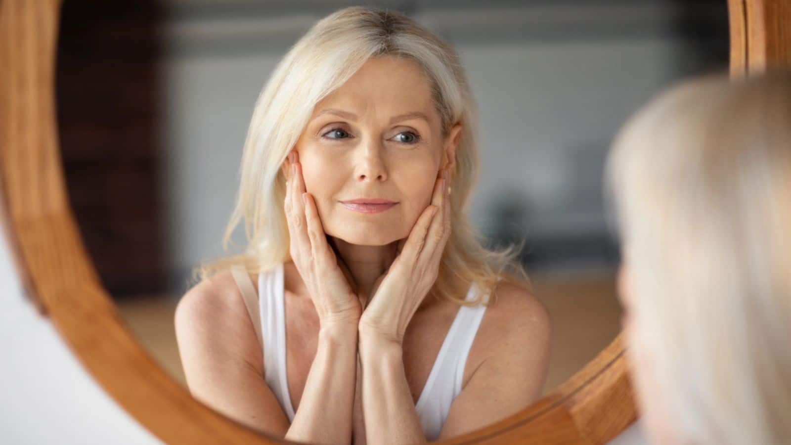 Happy woman looking at her face in the mirror