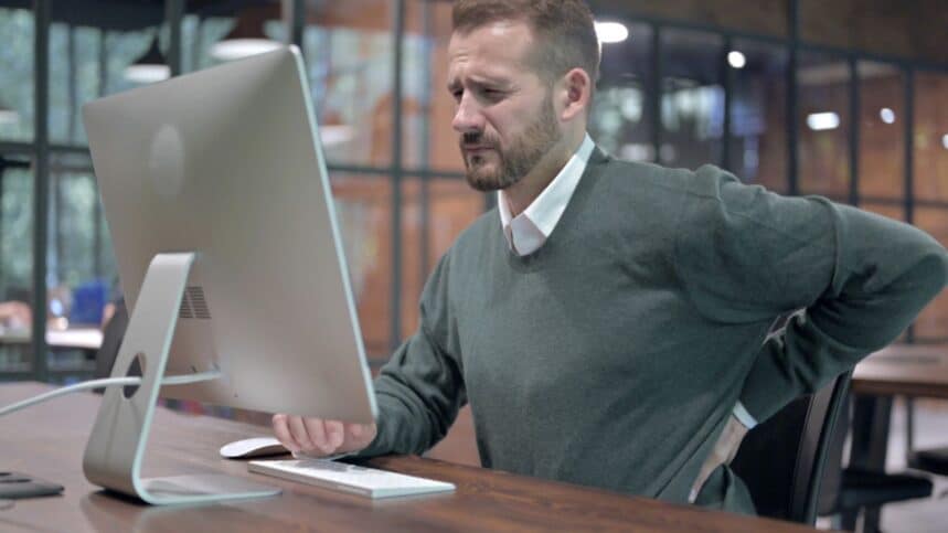 Man having back pain while working on desktop