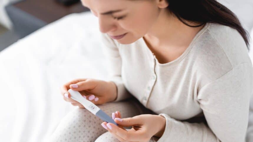 Sad woman crying while holding pregnancy test with negative result
