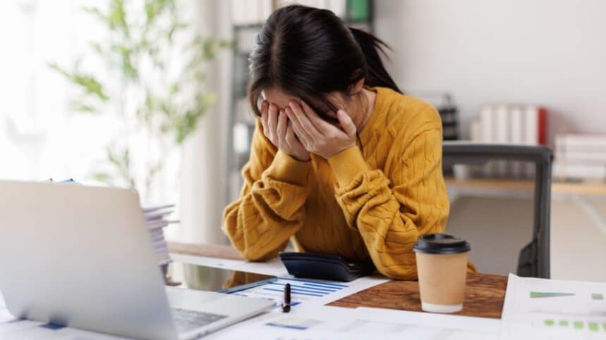 woman in a yellow sweater showcases a look of deep concentration mixed with stress