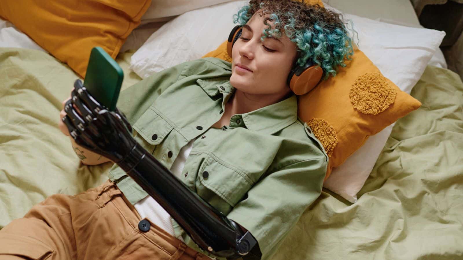 Smiling young woman with prosthetic arm listening to music