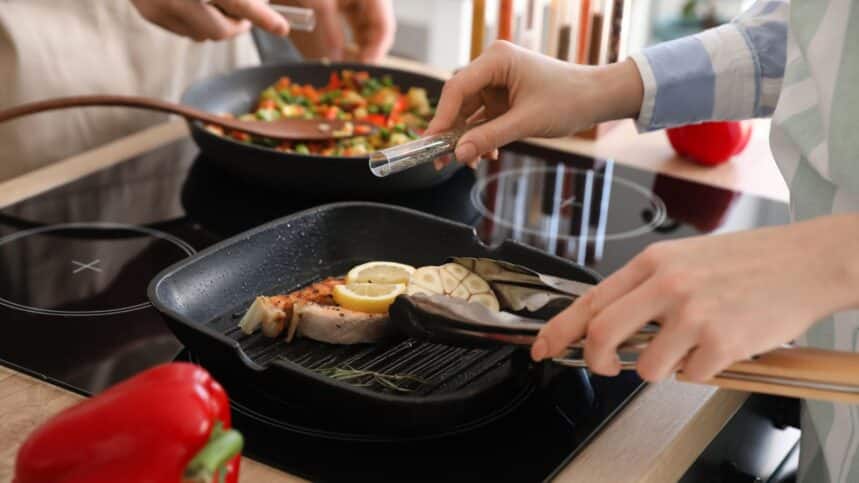 Woman frying tasty fish in kitchen, closeup