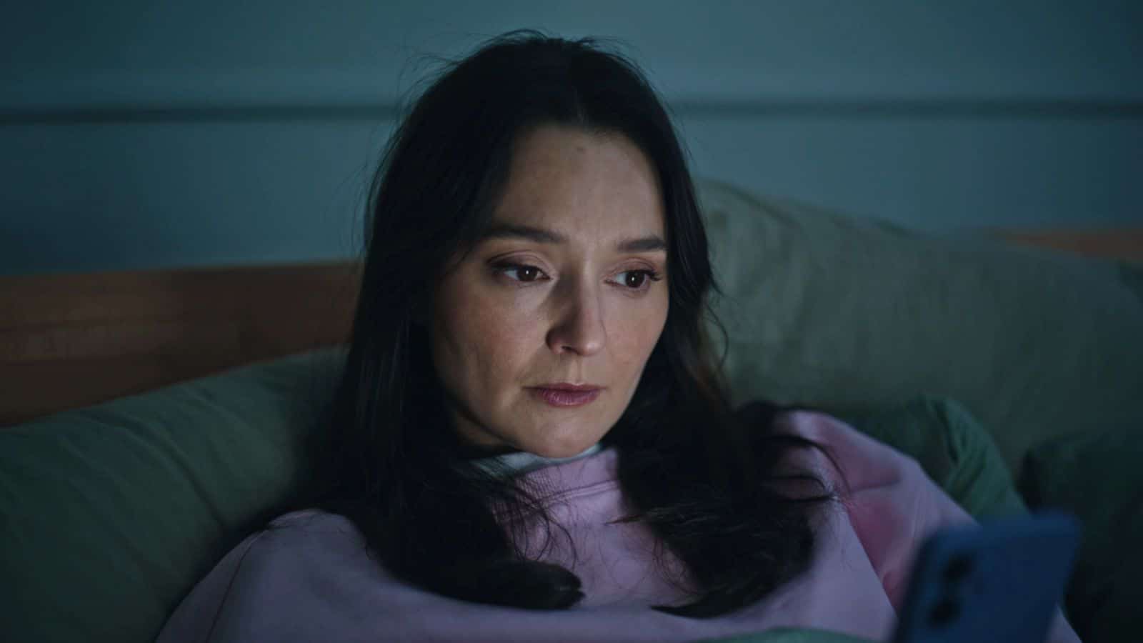 Woman scrolling on phone in bed late at night